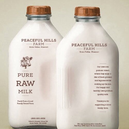 Two glass bottles of raw milk from Peaceful Hills Farm, Grain Valley, Missouri, featuring a rustic design. The labels highlight "Pure Raw Milk," emphasizing local sourcing and family-owned farming practices. The back label expresses gratitude for customer support and describes the farm's commitment to quality milk production.