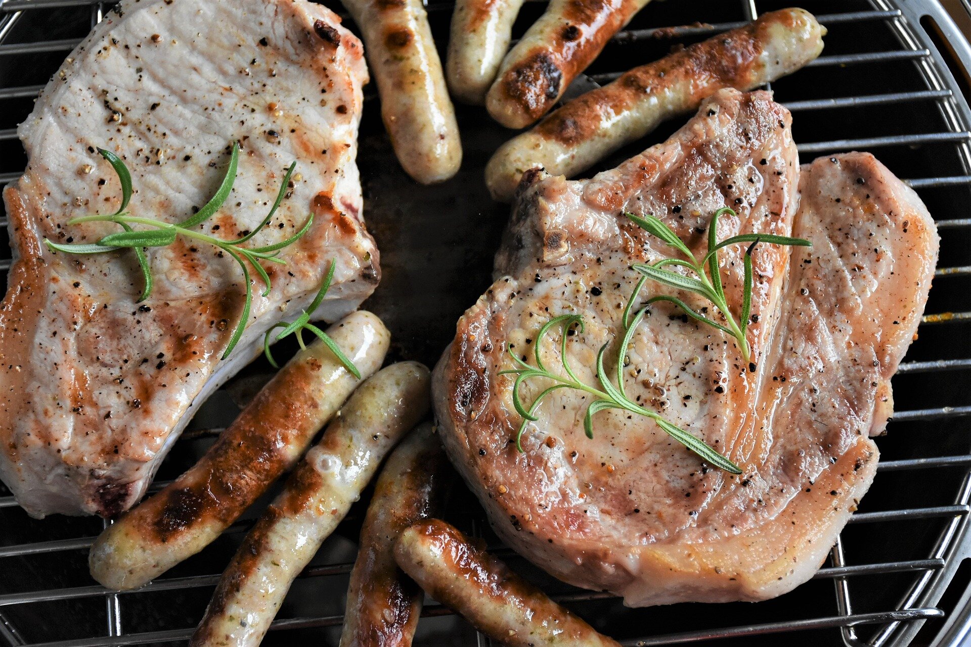 meat-4231141_1920 Grilled pork chops and sausages on a barbecue grill, garnished with fresh rosemary, showcasing a delicious and appetizing meal option.